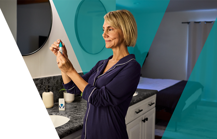 Woman in a bathroom looking at the Vyzulta bottle in her hand.